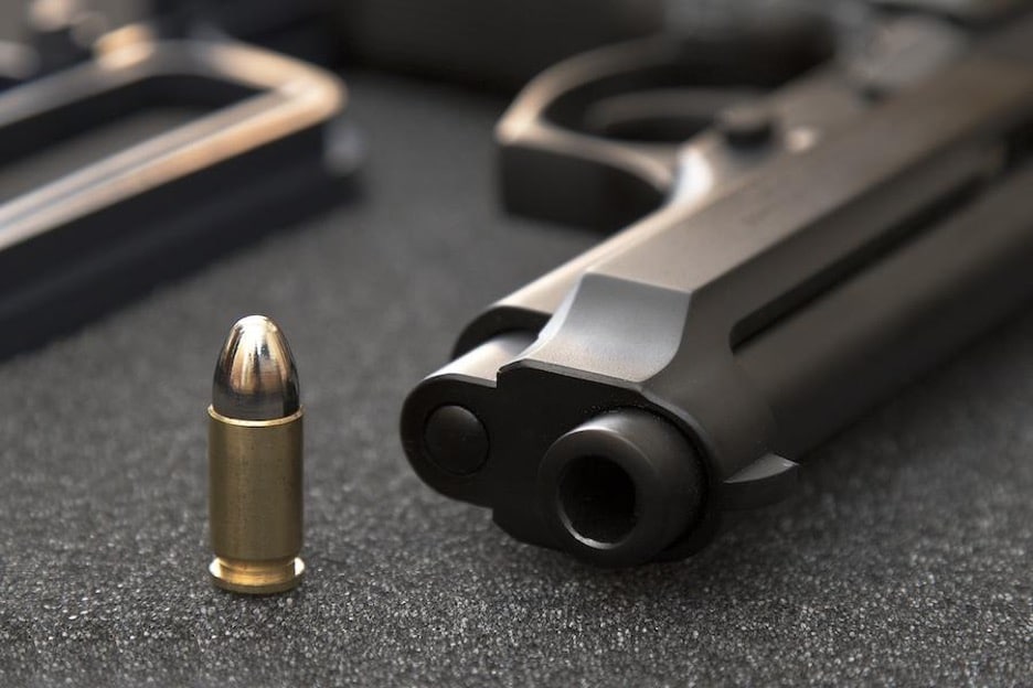 Handguns on desk with 9mm bullet